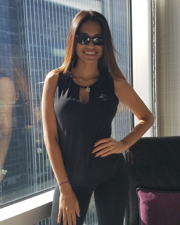 WBSAV CDO dressed in black, posing confidently by a large window, reflecting style, leadership, and the people behind the brand.